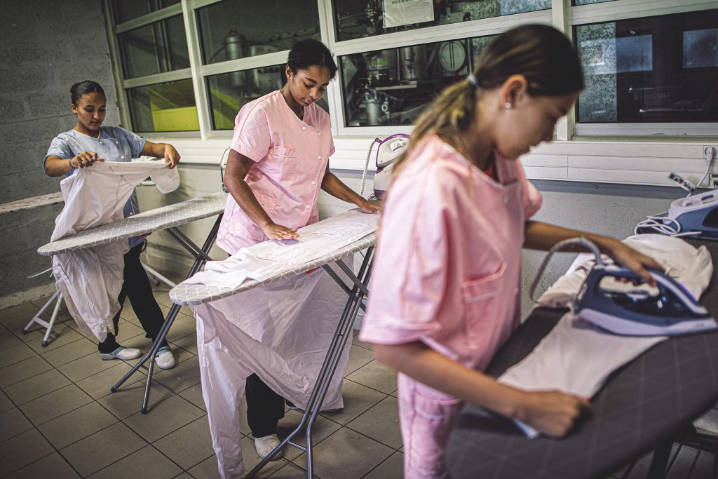 trois collégiennes repassent du linge