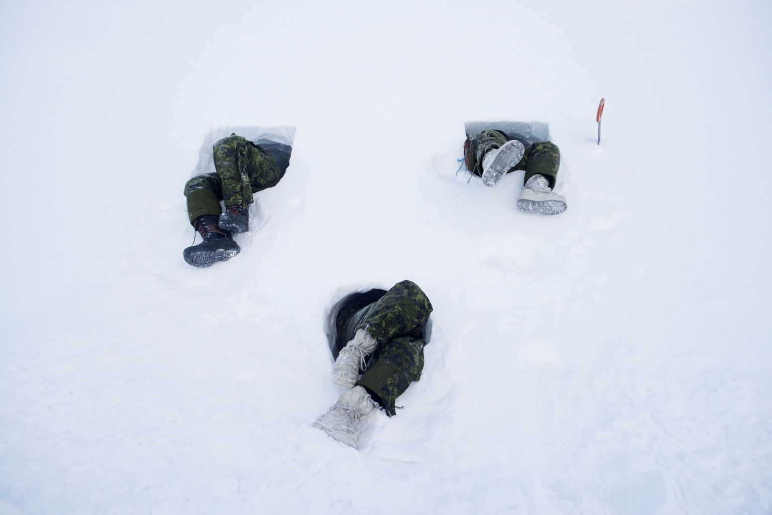 Des hommes creusent un tunnel dans le flanc d’une colline. Cet abri improvisé, appelé « grotte de neige », n’est chauffé que par une seule bougie. Les soldats envoyés dans le Grand Nord doivent apprendre à se repérer, manger, boire, dormir dans des températures extrêmes, allant de zéro l’été à -60 °C l’hiver.
