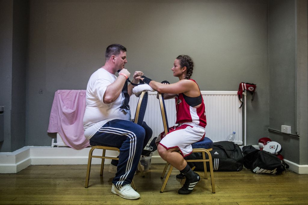 Dans une salle à l’écart, Emily Williams, reçoit, anxieuse, les derniers conseils de son entraîneur. C’est la première fois que la productrice de 28 ans va monter sur un ring. Elle fait partie de la poignée de femmes ayant suivi le programme d’entraînement intensif de White Collar Boxing London en vue d’un match public. La promesse de l’entreprise : « préparer les aspirants boxeurs – même celles et ceux qui n’ont que peu, ou aucune, expérience – à monter sur le ring en dix semaines. » Le site précise qu’il s’agit autant d’une « remise en forme que d’une opportunité pour faire de fantastiques rencontres. » Durant son entraînement, la jeune femme a surtout côtoyé des traders, des avocats d’affaires et quelques commerciaux, rapporte Andrew Testa.