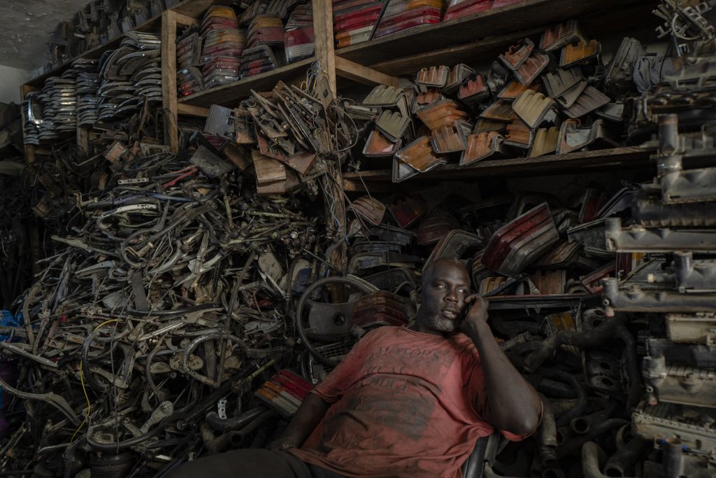 À l’intérieur de la boutique rose pâle, le vendeur siège devant ses trésors mécaniques. Toutes les pièces – démontées de 190 hors d’état de marche – sont stockées pour être revendues. « Avec leur exhaustivité et l’abondance de petits objets qui y règne, les magasins de pièces détachées mauritaniens ont des airs de pharmacie », observe le photographe. L’étalage offre un ordre certain : à droite, les radiateurs, au centre, les clignotants, en haut, la carrosserie. Et devant la formidable collection, ce vendeur qui, dans l’œil du photographe, « ne faisait presque plus qu’un avec l’arrière-plan. » Inutile de préciser qu’il est assis sur un fauteuil de Mercedes 190, transformé en siège de bureau.