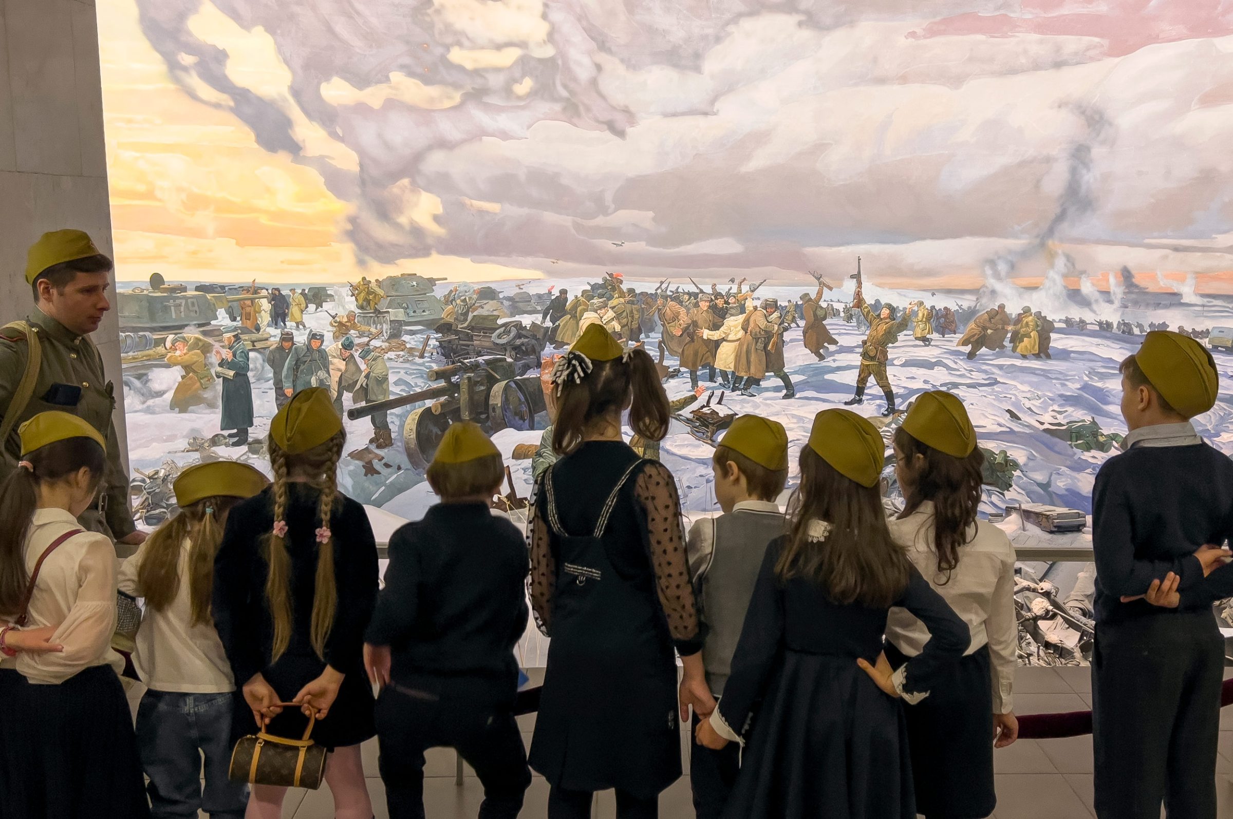 des enfants russes devant un tableau guerrier
