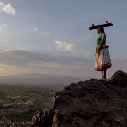 femme sur une colline, avec une planche de skate sur la t&ecirc;te