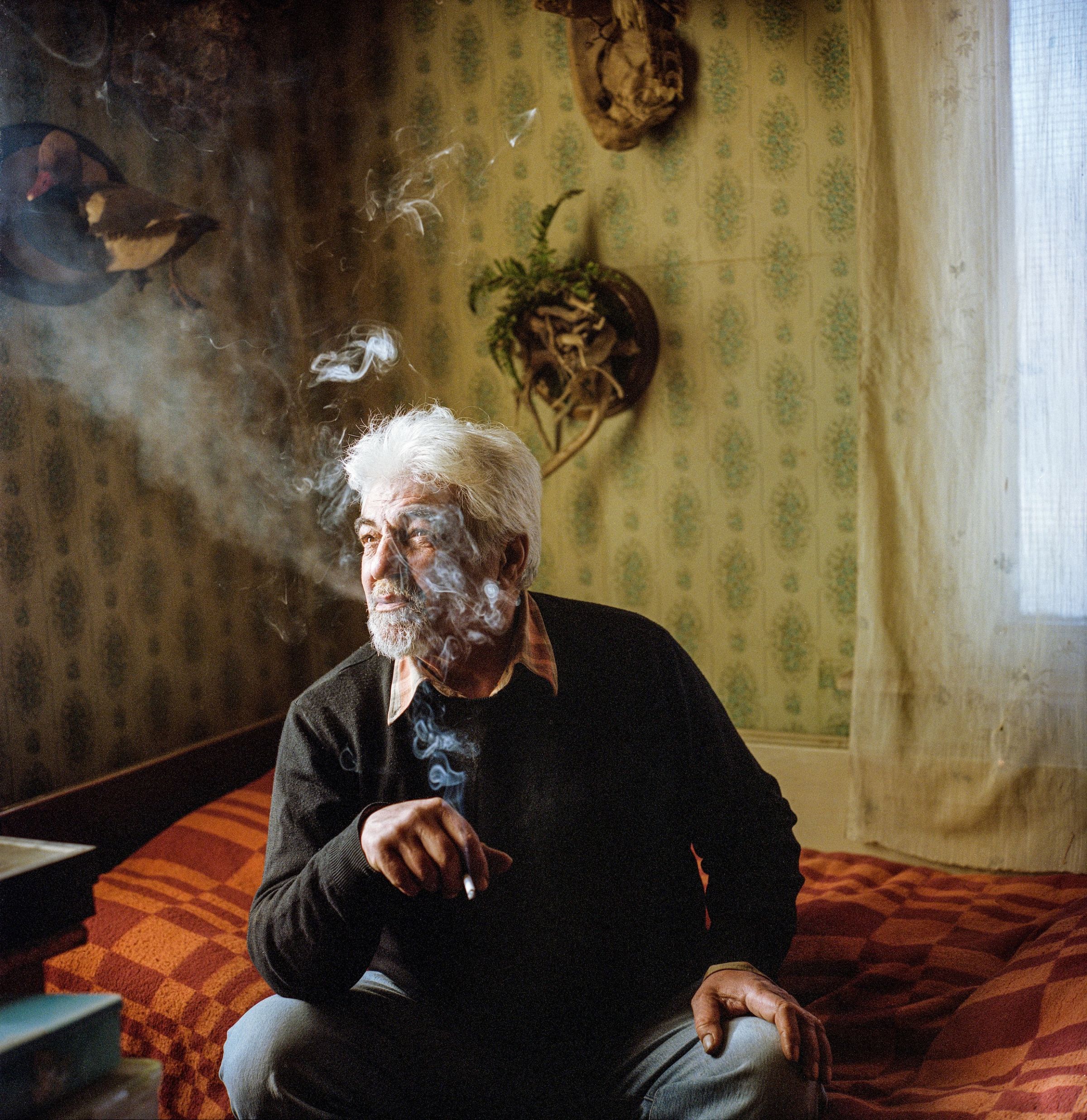 Parkev Kazarian, assis sur son lit chez lui dans le nord de l’Arménie, fumant une cigarette