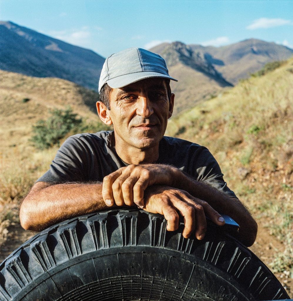 Portrait de Goga, conducteur de véhicule tout-terrain, appuyé sur un pneu