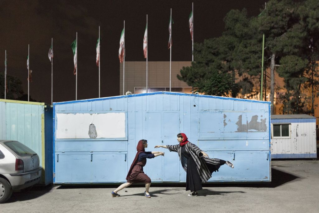 Deux jeunes femmes dansent devant une petite maison bleu en bois