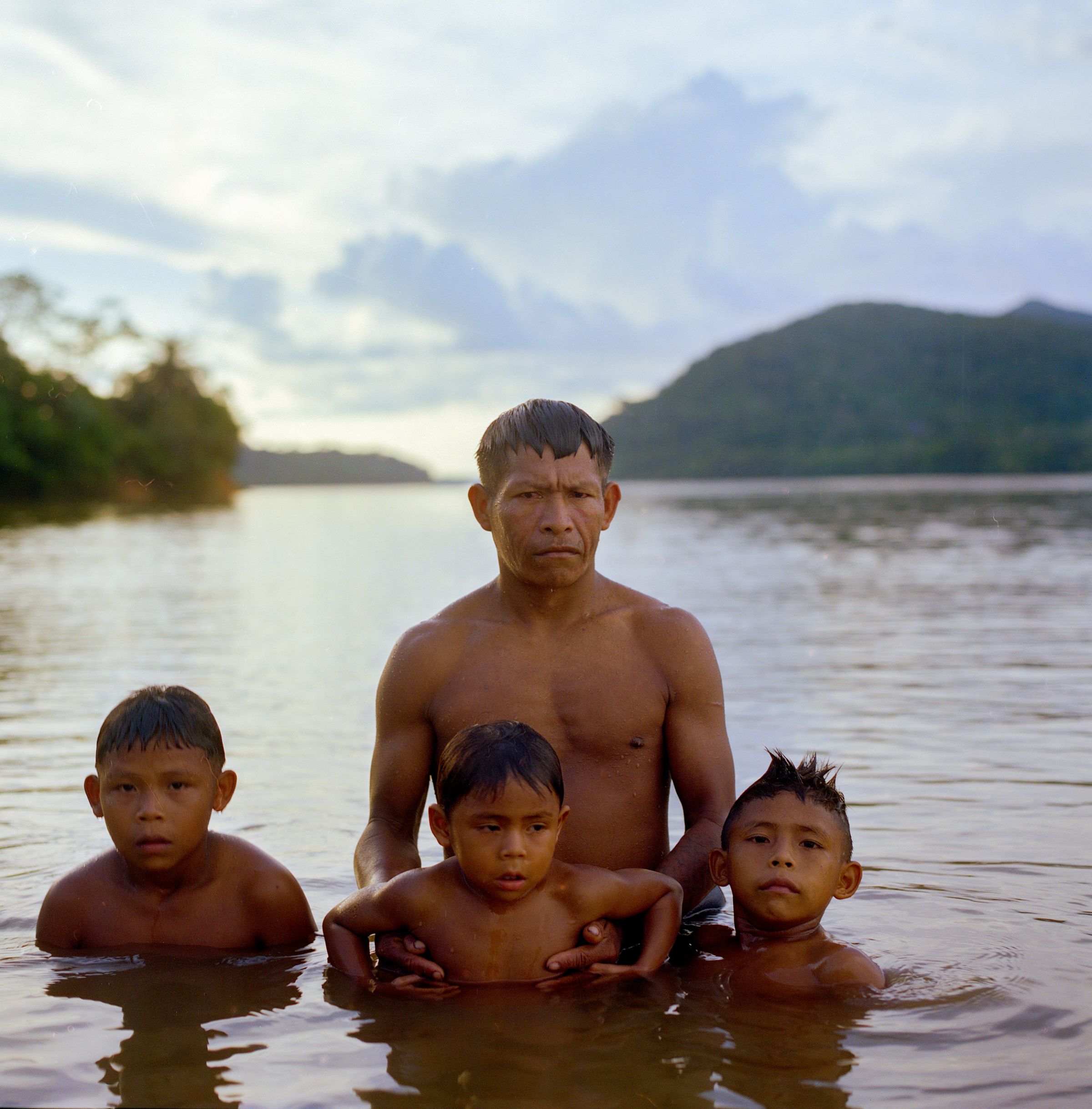 Un homme et ses trois enfants dans le fleuve en Amazonie.