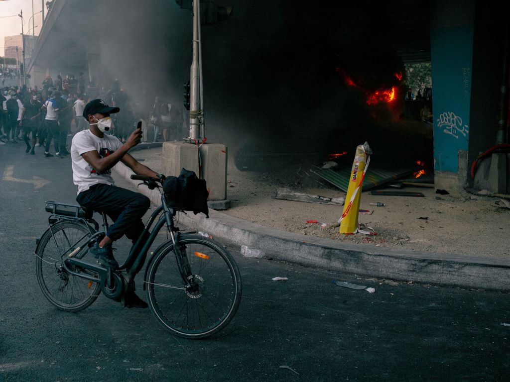 Un jeune homme sur un vélo prend une photo d'un feu avec son portable