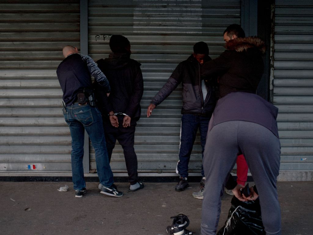 Interpellation de jeunes par la police devant une devanture de magasin fermé