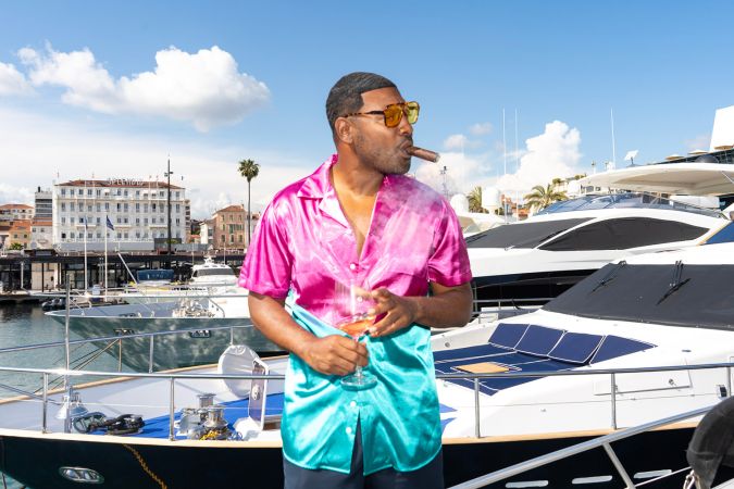 un homme avec un cigare pose devant un yacht