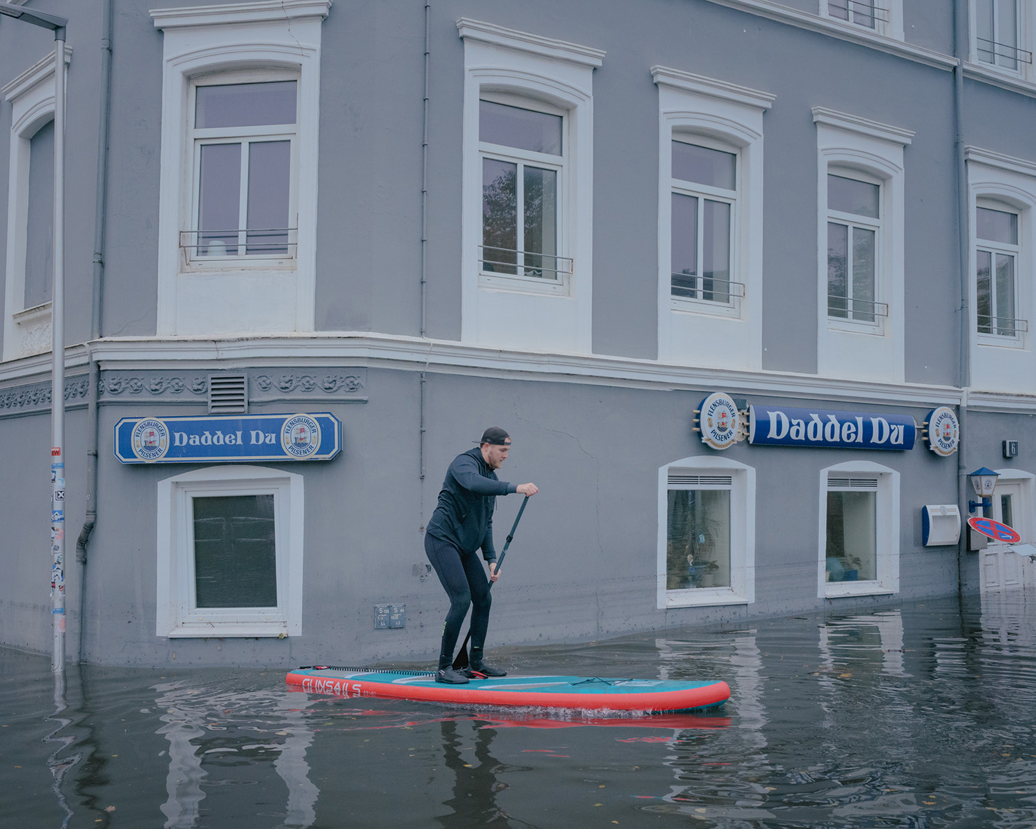 Un homme sur un paddle dans un centre ville inondé